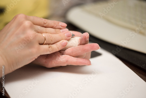 Girl hands polishing parts for making dolls from polymeric material.