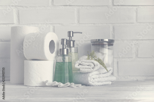Foggy part of spa interior. Cotton napkins, cotton pads, tissue, towels, soap and cosmetic products on wooden table. White background and table. Copy space. Selective focus.