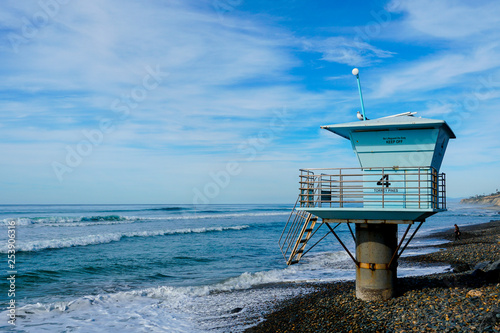 Blue lifeguard tower on a rocky sand beach with clouded blue sky sunny end of day, on Torrey Pines State Beach in California, located in San Diego County. © Unwind