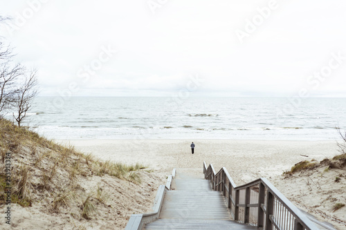 Fototapeta Naklejka Na Ścianę i Meble -  lonely man walks on the beach along the coastline, mora, huddy landscape