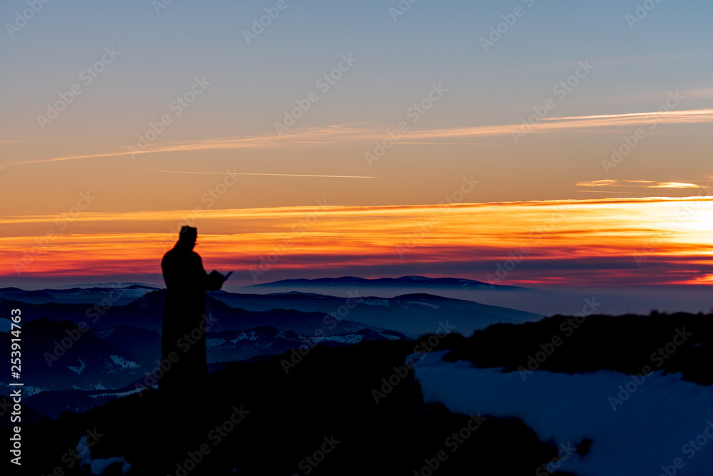 Obraz premium Priest silhoute reading in the sunset light, Romania