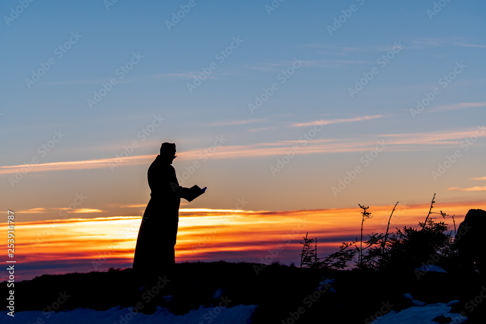 Priest silhoute reading in the sunset light, Romania