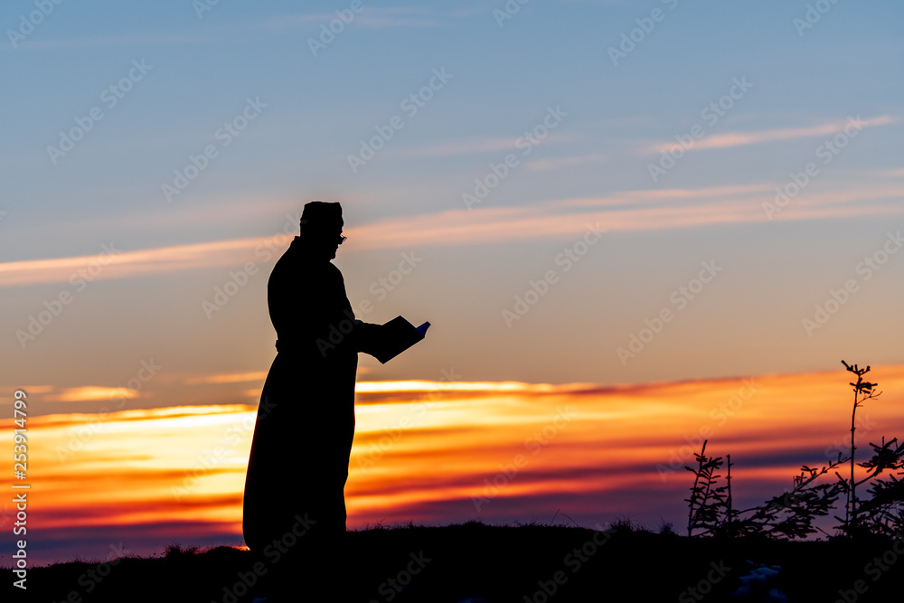 Priest silhoute reading in the sunset light, Romania Priest silhoute reading in the sunset light, Romania