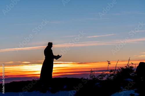 Priest silhoute reading in the sunset light  Romania