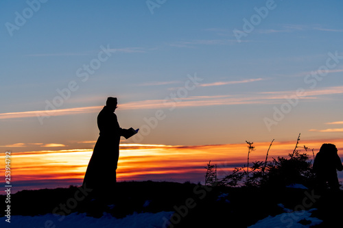 Priest silhoute reading in the sunset light, Romania