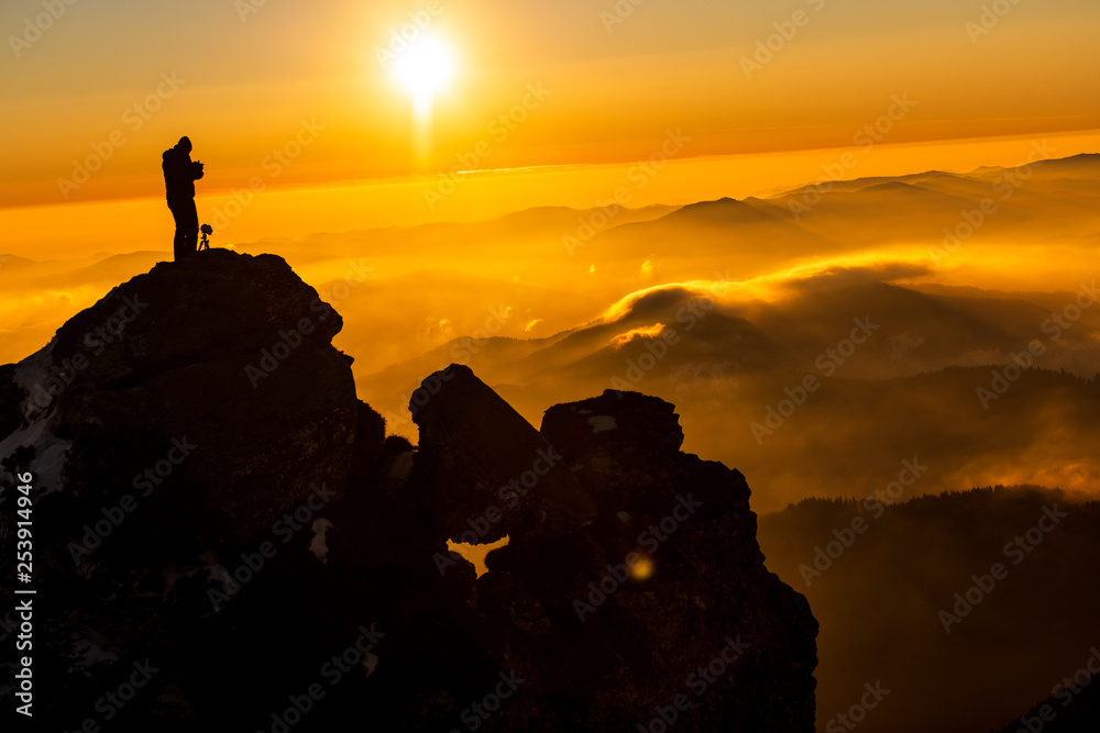 Red sunset and the silhoute of  photographer enthusiast stay on cliff and thinking..