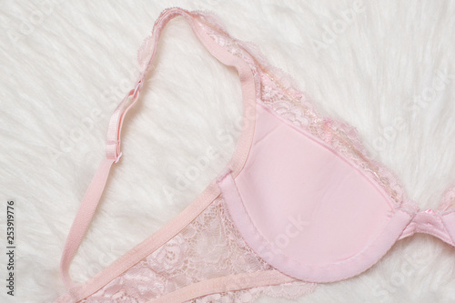 Pink lace bra on white fur, inner side. Flat lay. Fashion lingerie concept.