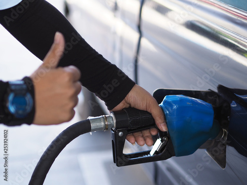 Closeup hand of man pumping gasoline fuel in car at gas station.