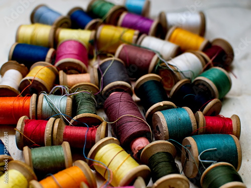 Old multi-colored coils lie in a box. A pile of coils with colored threads. Sewing supplies. Many coils of thread.