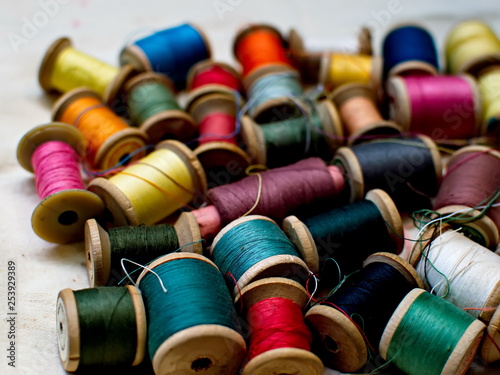 Old multi-colored coils lie in a box. A pile of coils with colored threads. Sewing supplies. Many coils of thread.