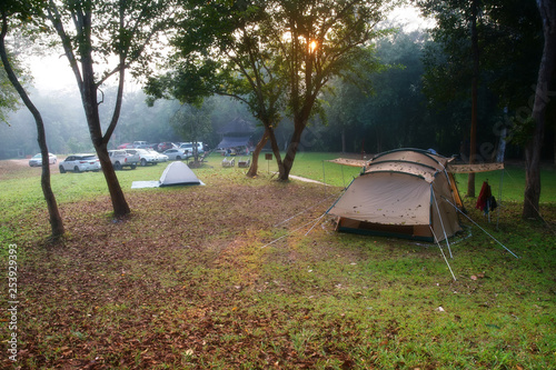 nature landscape camping tent with tree on green grass meadow and fog in jungle for trekking picnic on holiday relax and vacation travel on autumn winter or summer with warm sunlight at Ban Krang Camp