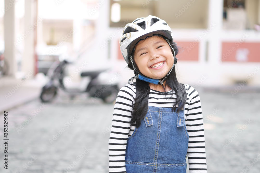 Asian child cute or kid girl wear white motorcycle or bike helmet with happy smiling white teeth for confident and head safety or sport exercise protect on street and road riding or driver travel Asian child cute or kid girl wear white motorcycle or bike helmet with happy smiling white teeth for confident and head safety or sport exercise protect on street and road riding or driver travel