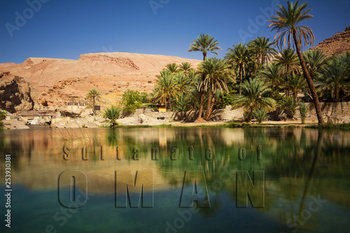 Wonderful lake and oasis with palm trees (Wadi Bani Khalid) in the Omani desert and overwritten text photo