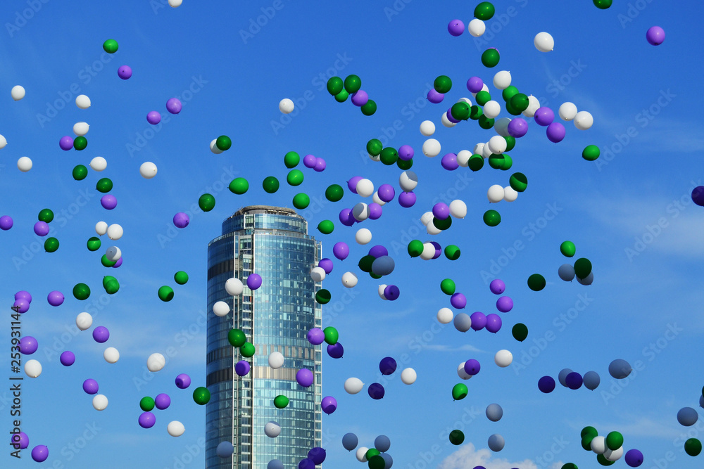 colorful balloons flying in the sky against the background of a skyscraper