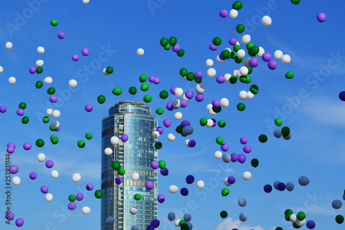 colorful balloons flying in the sky against the background of a skyscraper