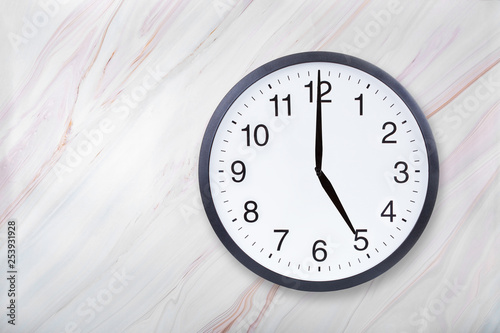 Wall clock show five o'clock on marble texture. Office clock show 5pm or 5am on marble texture with natural pattern photo
