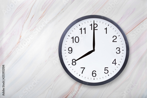 Wall clock show eight o'clock on marble texture. Office clock show 8pm or 8am on marble texture with natural pattern photo