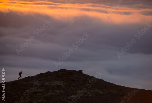 Silhouette of a man on the ridge above the sea of clouds, misty mountains at sunset in Iceland