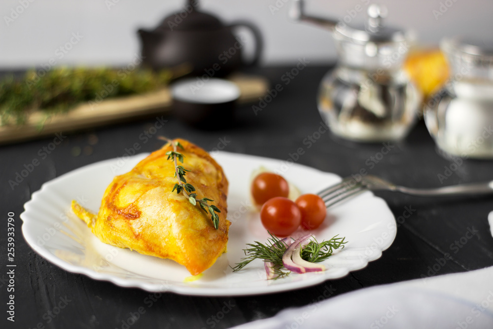 Baked chicken breast with onions and tomatoes on a white plate. Healthy food.