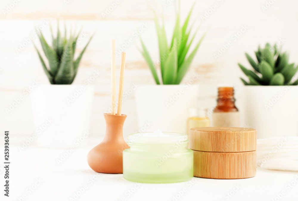 Homemade spa set, bath shelf with cream jars, essential oils, green plants background, light minimalist eco decor. Homemade spa set, bath shelf with cream jars, essential oils, green plants background, light minimalist eco decor.