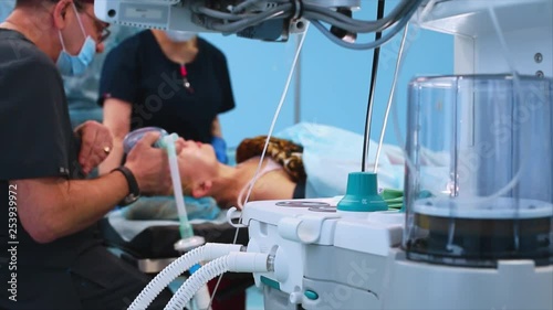 The operating room, the preparation of the patient for the operation, the anesthesiologist introduces the patient into anesthesia. View from behind the ventilator photo