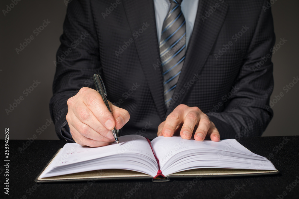 Businessman writing in a diary with a pen close up. Businessman writing in a diary with a pen close up.