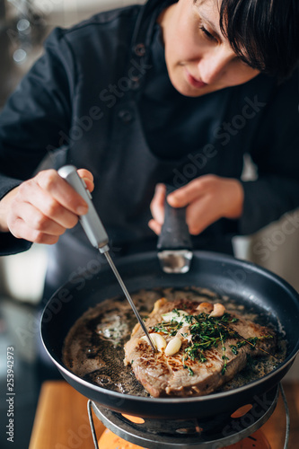 Chef measuring cooking temperature of steak frying on a skilet photo