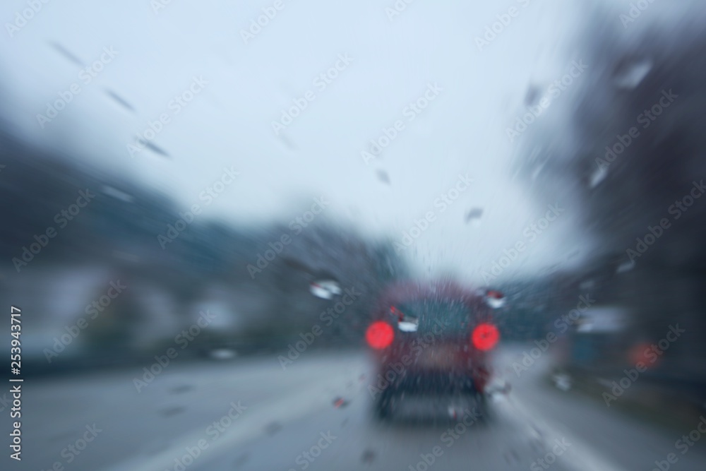 Driving a car after a rainy afternoon. Blurred view through the rear window of a car. Abstract background.