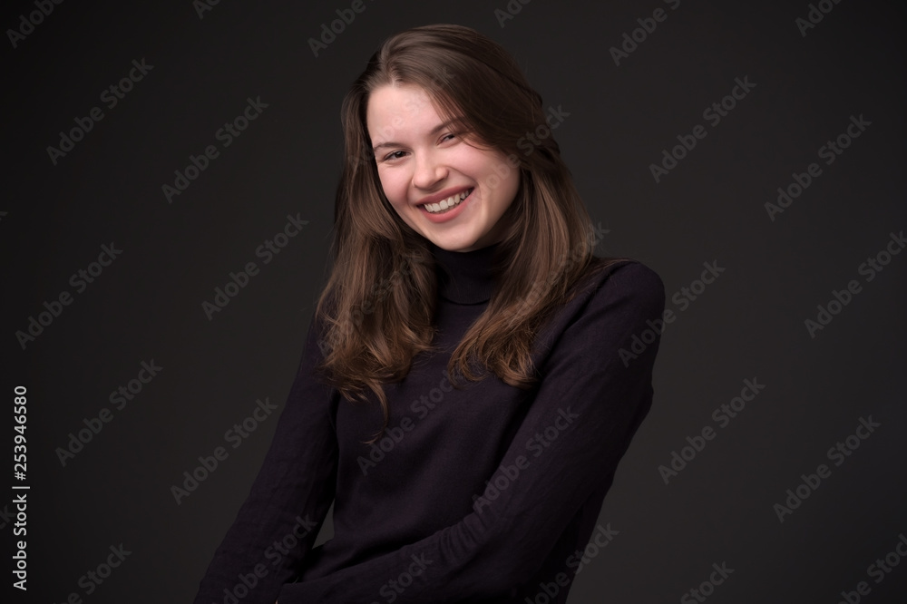 Laughing woman with long hair over black wall.