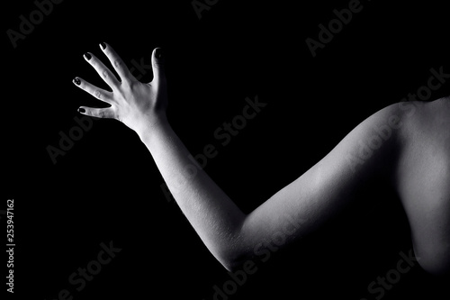 Close up of woman's hand and part of a shoulder isolated on black background.