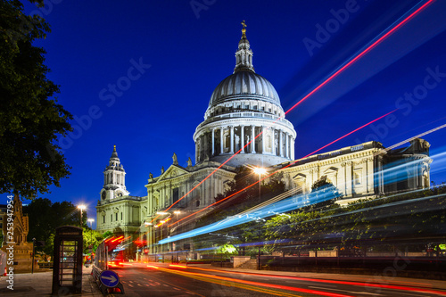 Fototapeta Naklejka Na Ścianę i Meble -  Night view of the beautiful facade of St Paul's Cathedral in the City of London, London, England, with the iconic red bus passing by. The dome of the church is one of the largest in the world