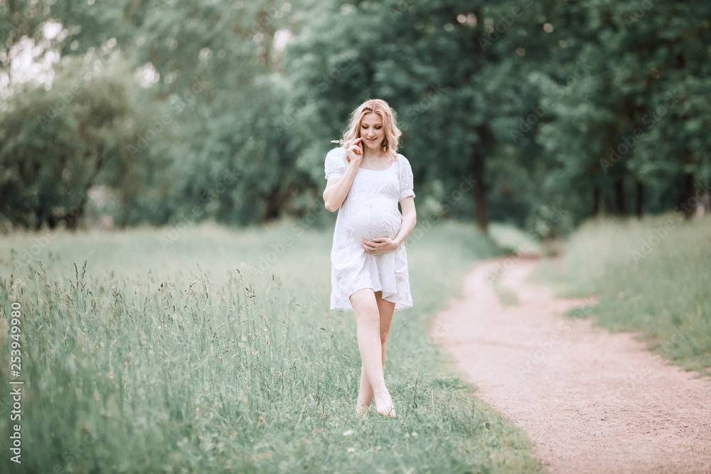 rear view. pregnant woman walking barefoot on grass. rear view. pregnant woman walking barefoot on grass.