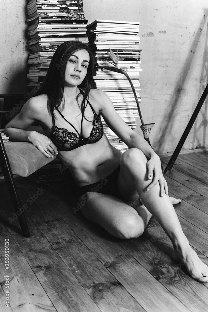 Naklejka premium Sexy lady in lace lingerie with long black hair looking at camera. Black and white photo