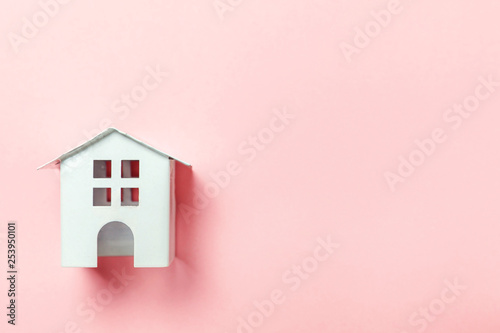 Simply design with miniature white toy house isolated on pink pastel colorful trendy background. Mortgage property insurance dream home concept. Flat lay top view copy space