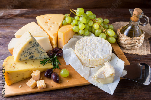 Cheese plate served with grapes on a wooden background