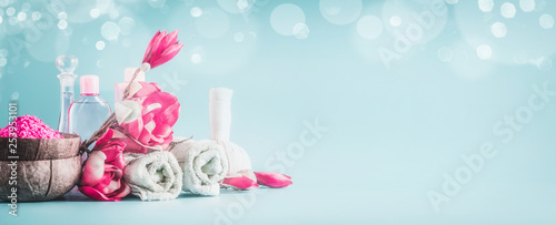 Beautiful spa setting banner or template with towels, flowers, candles and body care cosmetics at light blue background,  copy space. Beauty concept