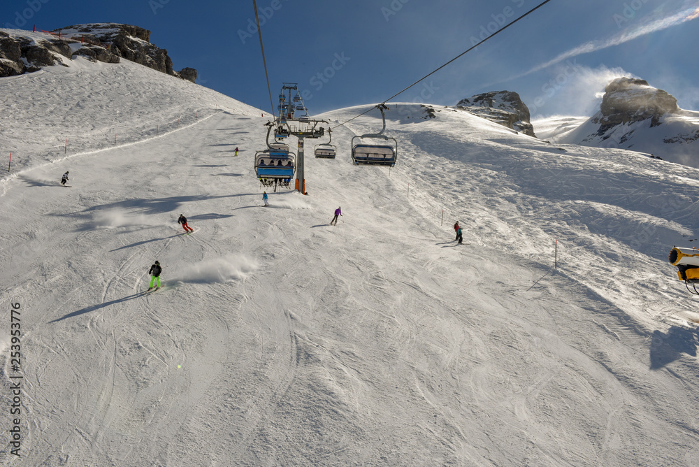 People skiing and going up the mountain by chairlift at Engelberg on the Swiss alps
