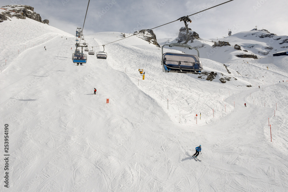People skiing and going up the mountain by chairlift at Engelberg on the Swiss alps People skiing and going up the mountain by chairlift at Engelberg on the Swiss alps
