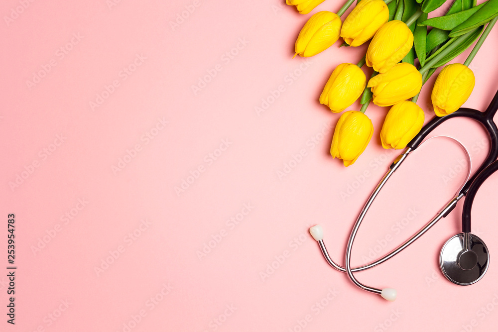 Bunch of yellow tulips and stethoscope on pink background. National Doctor's day. Happy nurse day.