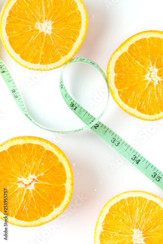 slices of fresh orange on a white background and measuring tape