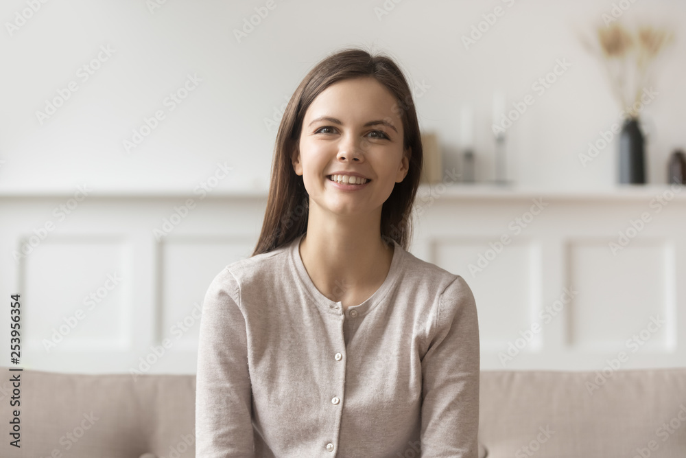 Smiling young casual woman sitting on couch looking at camera Smiling young casual woman sitting on couch looking at camera