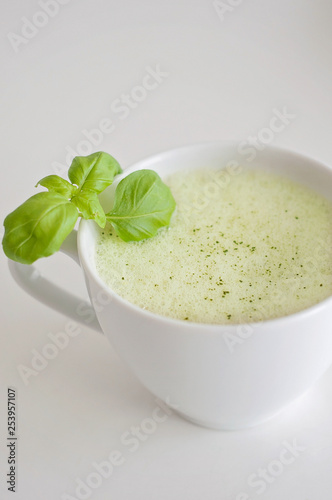 Healthy green tea matcha latte with soy and oat milk in a white tea cup decorated with basil and foam on top - a warm beverage to boost brain function and as a cancer prevention!