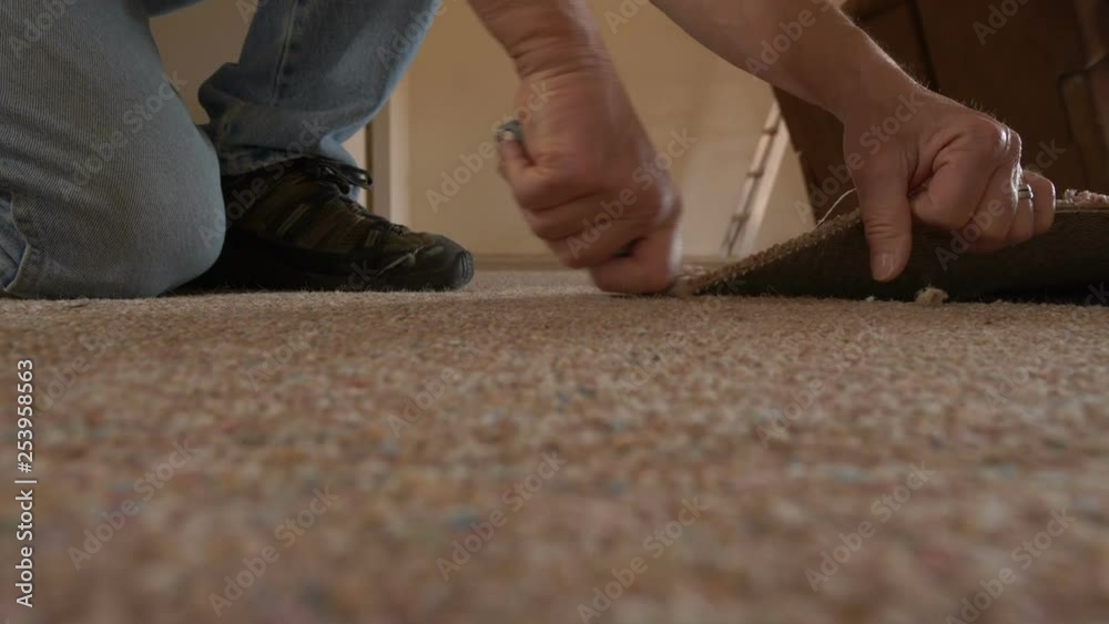 A man cutting out old carpeting on a home remodel
