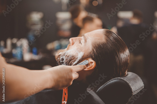 Man hipster having barber shave the barbershop