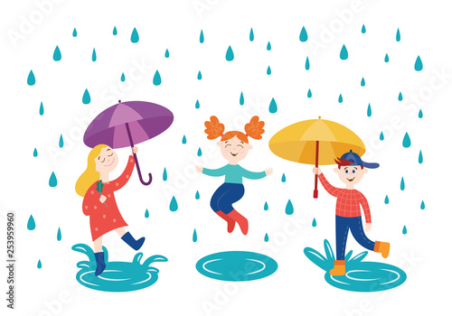 Cheerful children playing and jumping under umbrella in rainy weather outdoors in autumn.