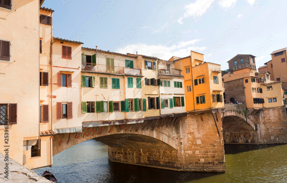 Sunny day at bridge Ponte Vecchio in historical Florence, Tuscany. River and ancient cityscape in Italy