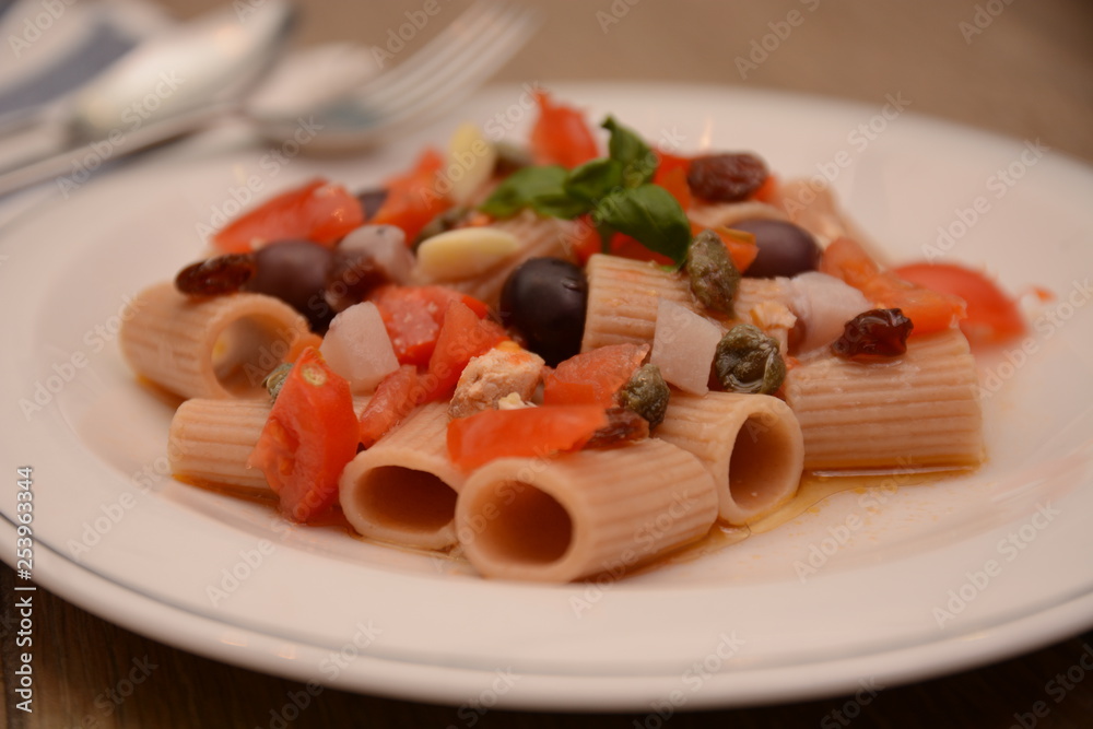 pasta con pescespada pomodori capperi olive nere uva sultanina basilico piatto tipico della sicilia sud italia sapori mediterranei