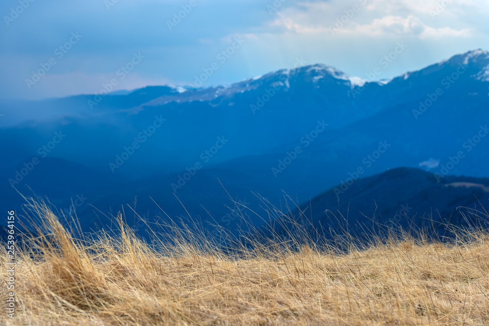 Early spring in the mountains, with peaks still covered with snow. Panoramic view of a natural alpine landscape in a sunny day, with majestic Bucegi mountains in the Carpathians.