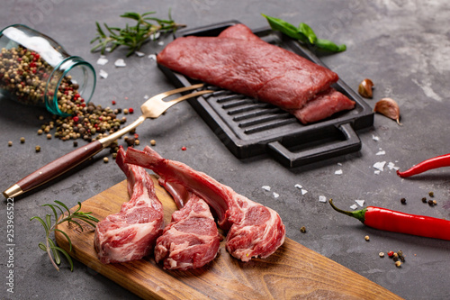 Фотография Set of Raw uncooked black angus beef tomahawk steaks on bones and veal tenderloin served with chilli and peppercorns