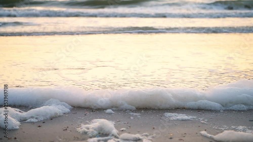 Closeup of red tide algae bloom toxic foam crashing in Naples beach in Florida Gulf of Mexico during sunset on sand photo